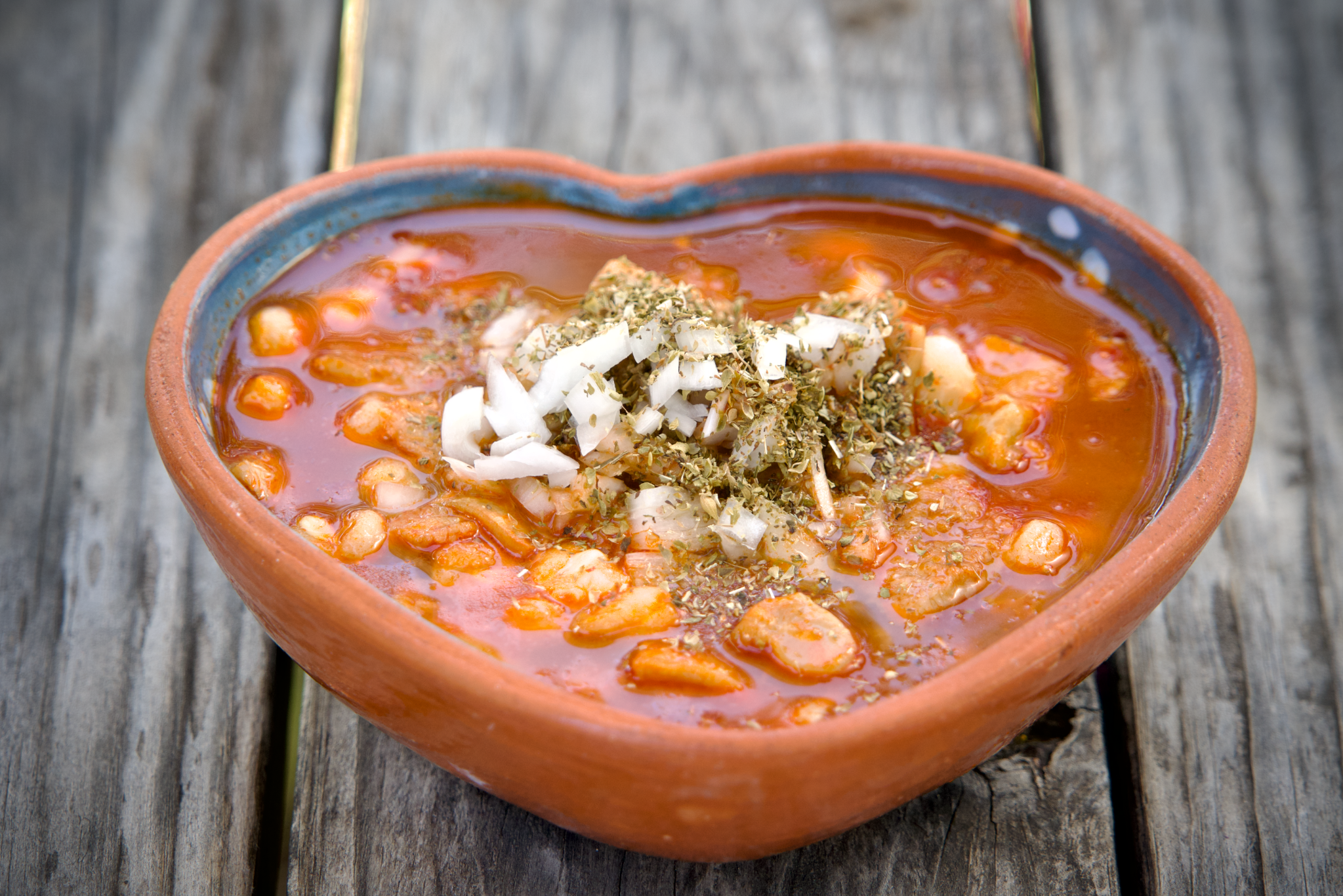 Menudo in red broth topped with chopped onion and oregano